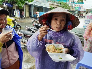 Bà cụ vừa nhận hộp cơm vội mở ăn ngay tại chỗ, cụ còn được phát 2 hộp đem về cho cháu. (Ảnh: TTO) 