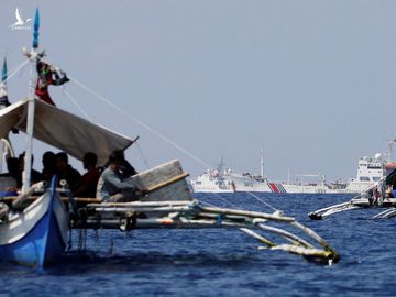 Thuyền banca chèo tay của ngư dân Philippines tại bãi cạn Scarborough. Xa xa là các tàu công vụ của Trung Quốc.