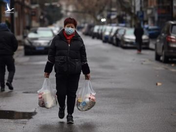 Một phụ nữ đi bộ trên đường phố Vũ Hán sau khi từ chợ về ngày 26/1. Ảnh: AFP.