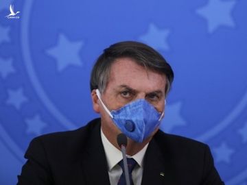 Tổng thống Brazil Bolsonaro đeo khẩu trang trong cuộc họp báo về Covid-19 tại Brasilia hôm 20/3. Ảnh: AFP.