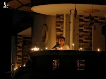 Một phụ nữ thắp nến ở ban công chung cư tại thành phố Ahmedabad tối qua. Ảnh: Reuters