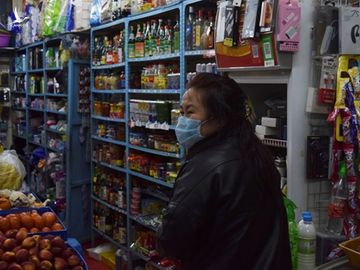 Chủ tiệm tạp hóa ở Tuy Phân Hà đeo khẩu trang tiếp khách hôm 15/4. Ảnh: Reuters.