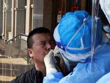 Cán bộ kiểm dịch thành phố lấy mẫu xét nghiệm nCoV hôm 16/4. Ảnh: Reuters.