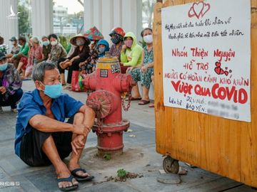 Những người dân có hoàn cảnh khó khăn ngồi chờ nhận quà từ một nhóm từ thiện trên đường Lý Chính Thắng (quận 3, TP HCM) chiều 3/4. Ảnh: Nguyệt Nhi.