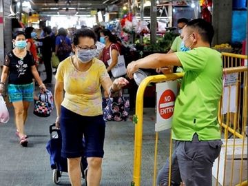 Người dân xịt khử trùng tay trước khi rời khỏi chợ ở Singapore ngày 23/4. Ảnh: Reuters.