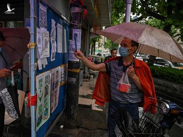 Người đàn ông dùng điện thoại chụp thông tin trên một bảng tin ở thành phố Vũ Hán, hôm 14/5. Ảnh: AFP.