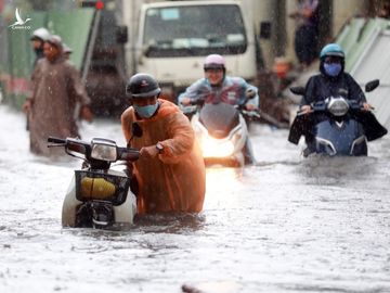 Người dân dắt xe chết máy trong cơn mưa lớn chiều 16/6 trên đường Nguyễn Hữu Cảnh (quận Bình Thạnh). Ảnh: Hữu Khoa.