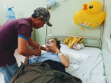 Bà Phạm Thị Lệ Thủy đang được chồng chăm sóc tại bệnh viện. Ảnh: Việt Quốc.