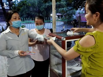 18h30, chị Huỳnh Thị Hoàng (bìa trái) lấy vé số tại đại lý để bán sau một ngày làm việc tại công ty. Ảnh: Hoàng Nam.