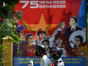 Hai thanh niên đi qua áp phích chào mừng ngày Quốc khánh hôm 1/9. Ảnh: AFP.