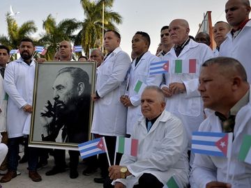 Đoàn bác sĩ quốc tế Cuba Henry Reeve cầm ảnh chân dung cố lãnh tụ Fidel Castro trước khi lên đường tới Italy hôm 21/3. Ảnh: AFP.