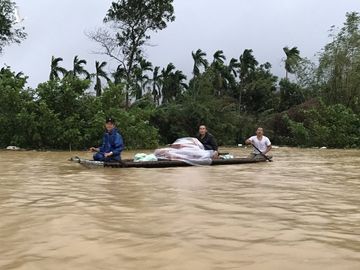 Người dân xã Hương Toàn (thị xã Hương Trà) chèo thuyền giữa nước lũ nhận mì tôm, nhu yếu phẩm cứu trợ. Ảnh: Hoàng Táo