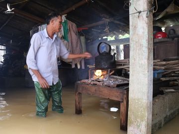 Ông Nguyễn Văn Liễu lội trong nước , thay vợ nấu ăn ngày lũ. Ảnh: Hoàng Táo