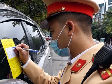 Tổ công tác thuộc Đội CSGT số 6 dán phiếu thông báo phạt nguội trên xe ôtô dừng đỗ trên phố Duy Tân, Cầu Giấy ngày 15/12. Ảnh: Văn Lộc