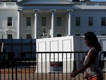 Một người phụ nữ đi qua phía trước Nhà Trắng hồi tháng 7/2019. Ảnh: Reuters.
