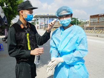 Một tài xế chở hàng được đo thân nhiệt, rửa tay sát khuẩn khi vào địa phận tỉnh Đồng Nai sáng 5/6. Ảnh: Phước Tuấn