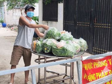 Người dân trong khu vực phong tỏa ở H.Hóc Môn (TP.HCM) nhận quà hỗ trợ là rau xanh từ các nhà hảo tâm ẢNH: S.Đ