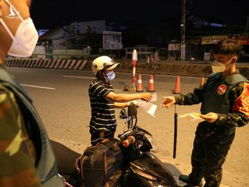 Người đi xe máy bị kiểm tra giấy tờ và yêu cầu khai báo qua phần mềm tại chốt kiểm soát cầu Vĩnh Bình, TP Thủ Đức, tối 12/8. Ảnh: Đình Văn