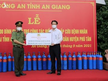 Đại tá Đinh Văn Nơi - Giám đốc Công an tỉnh An Giang - trao biển tượng trưng chương trình hỗ trợ 2.000 bình ôxy cho Giám đốc Sở Y tế An Giang. Ảnh: CA An Giang