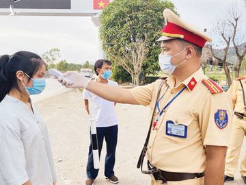 Cảnh sát giao thông Công an tỉnh Thanh Hóa kiểm tra thân nhiệt hành khách trên xe khách di chuyển qua khu vực chốt kiểm soát giao thông. Ảnh: Báo Nhandan.