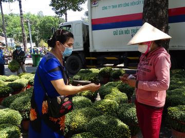 Một người dân (trái) tới mua hoa ủng hộ gia đình anh Thiện. Ảnh: Hà An