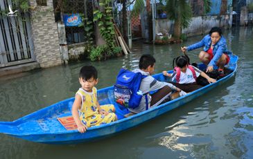 Người dân TP.HCM chèo xuồng đưa con đi học vì đường ngập mãi không hết