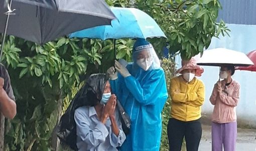 Nữ tình nguyện viên ở TP.HCM cầm ô che cho cụ già dưới trời mưa lớn